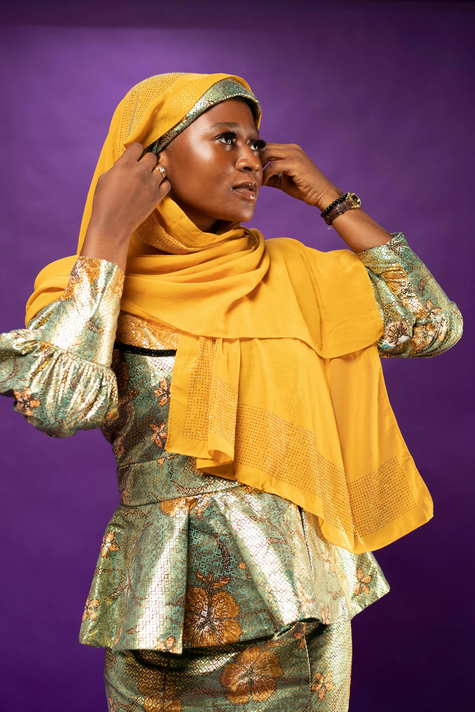 a woman in a gold blouse and dress standing