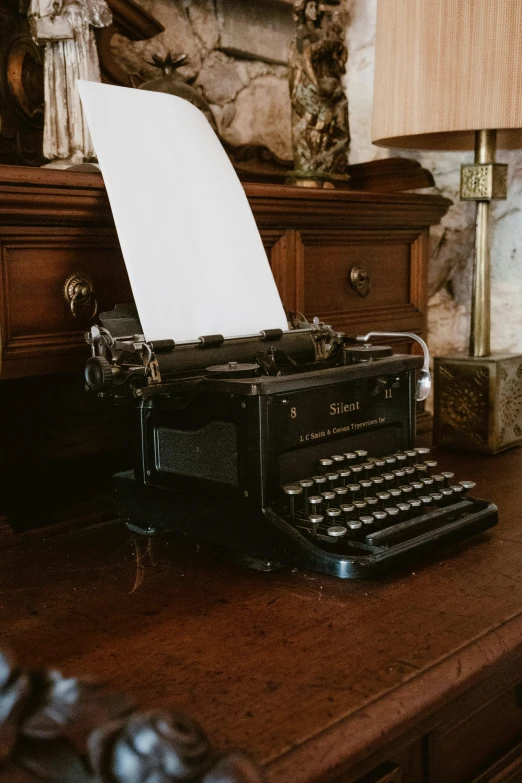 an old fashioned typewriter and lamp on top of a table