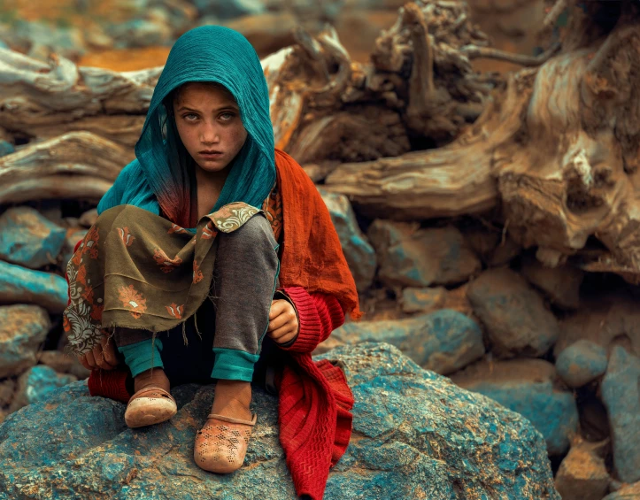 young woman dressed in indian clothing sitting on a rock