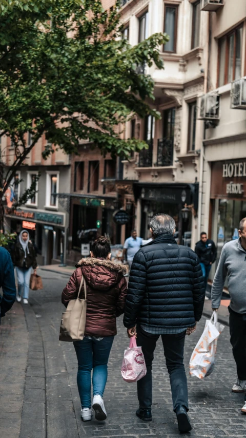 some people are walking down a street with bags