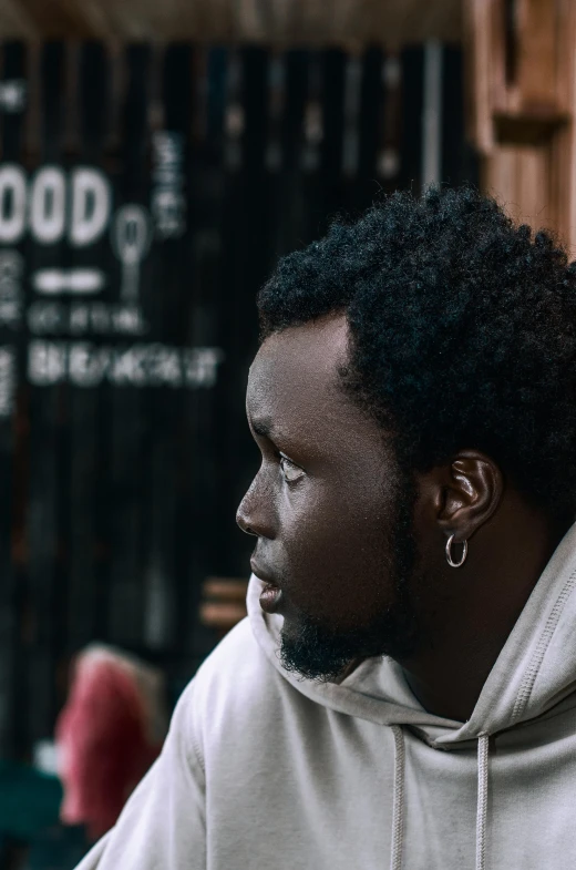 black man with afro in a white sweatshirt staring away