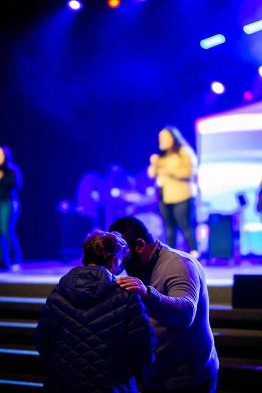 two people in a concert are sharing a hug