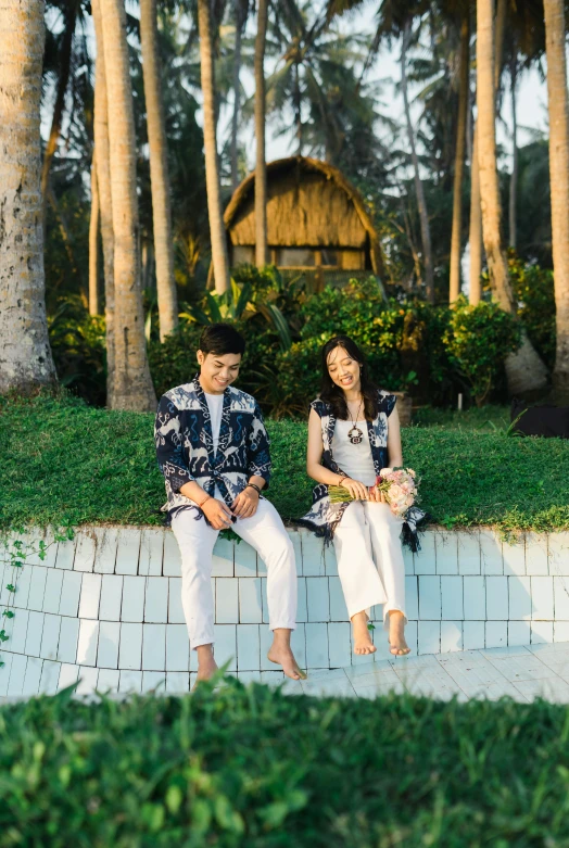 two people sitting on top of a brick bench next to each other