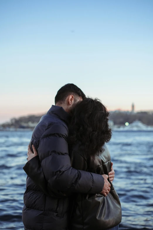 a young couple is in love hugging by the water