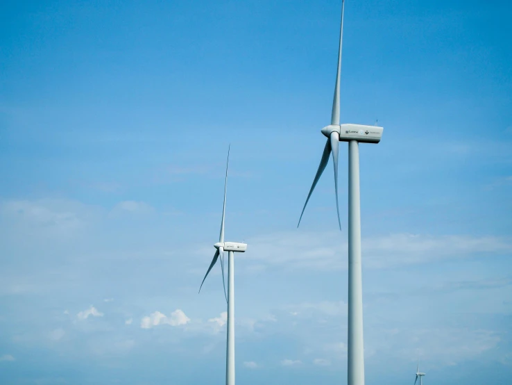 three wind mills with the sky behind them