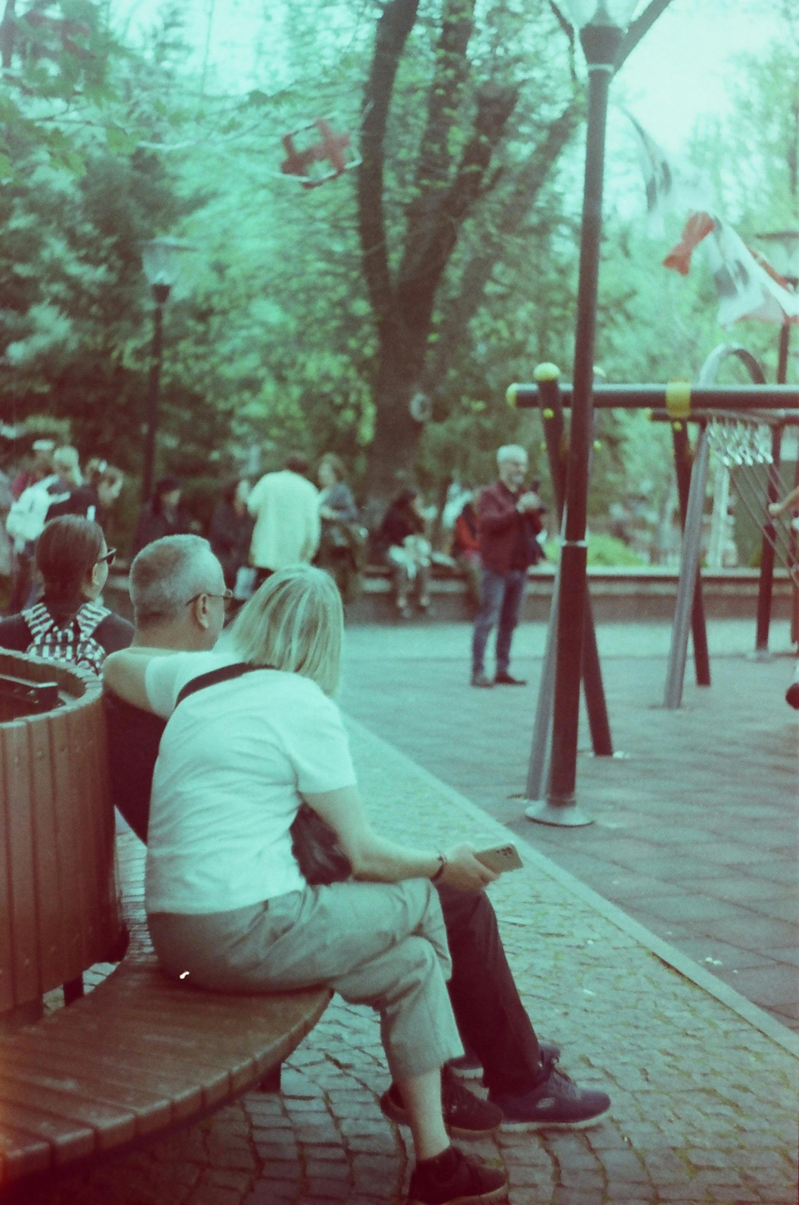 some people sitting on a bench and people walking around