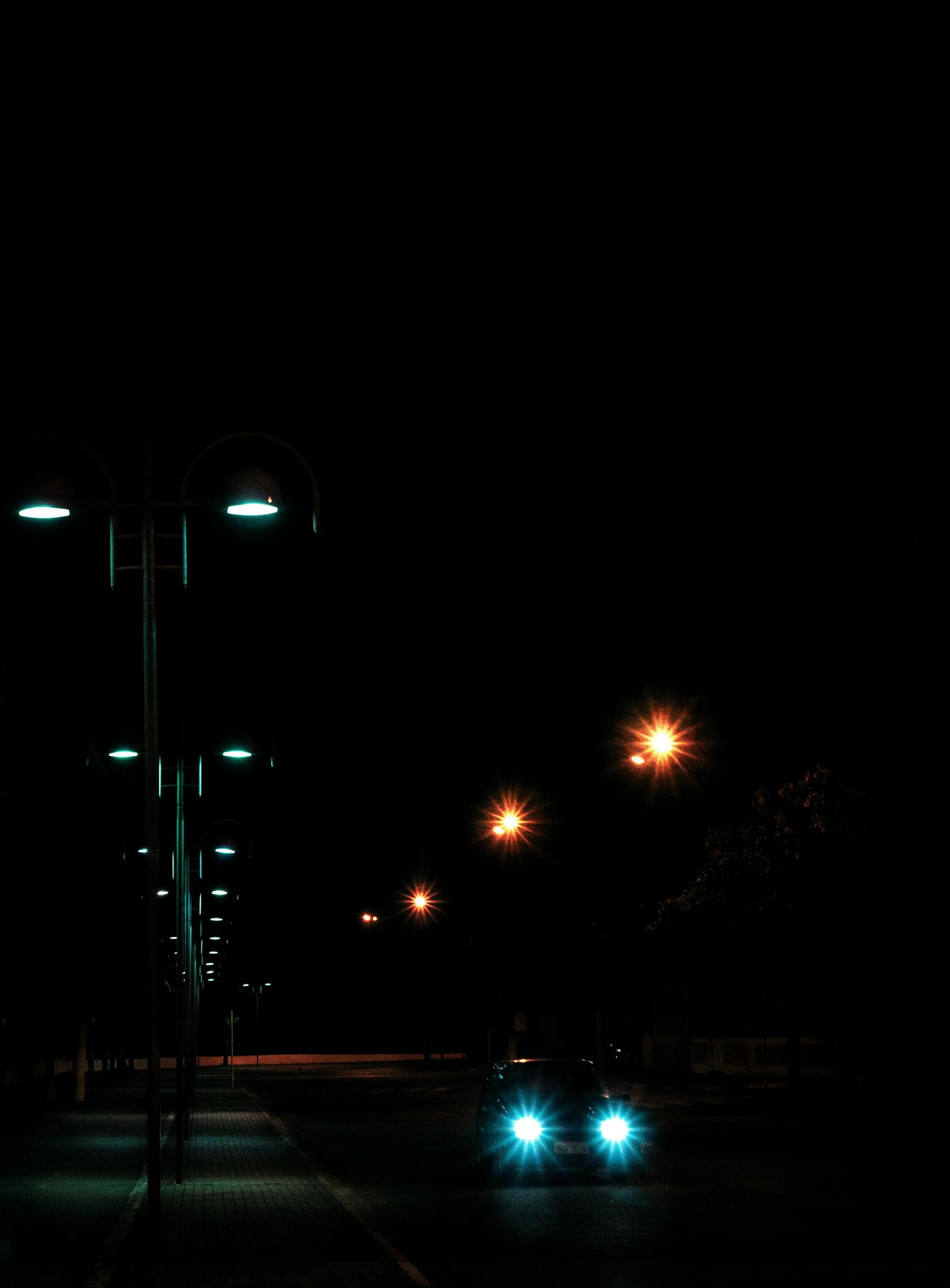 a street light, two blue cars in the dark