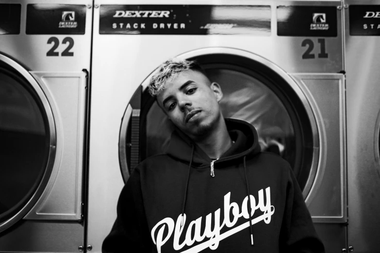 a guy with his eyes closed standing near a washer