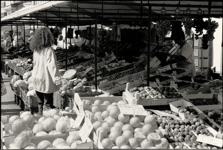 a woman looking at an array of fruits and vegetables