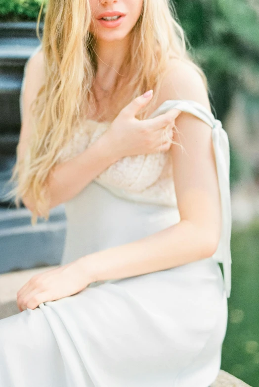 the blonde woman with a crown on her head is posing in front of a fountain