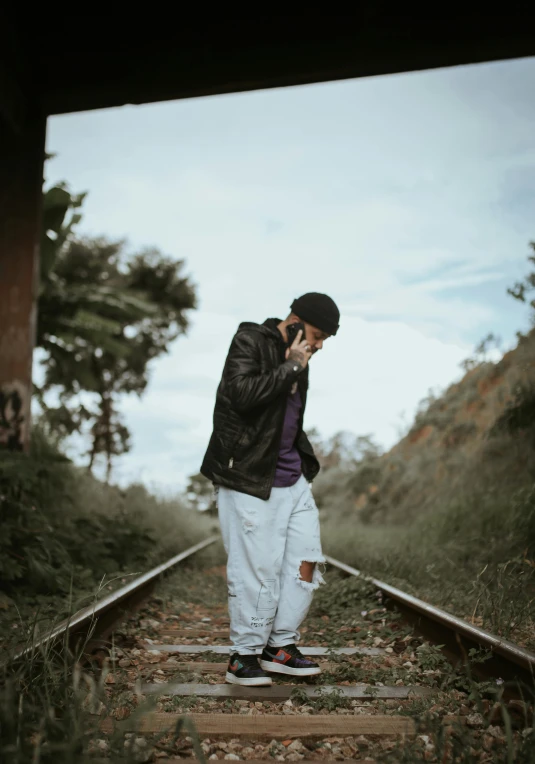 a man is standing on an old train track talking on his cellphone