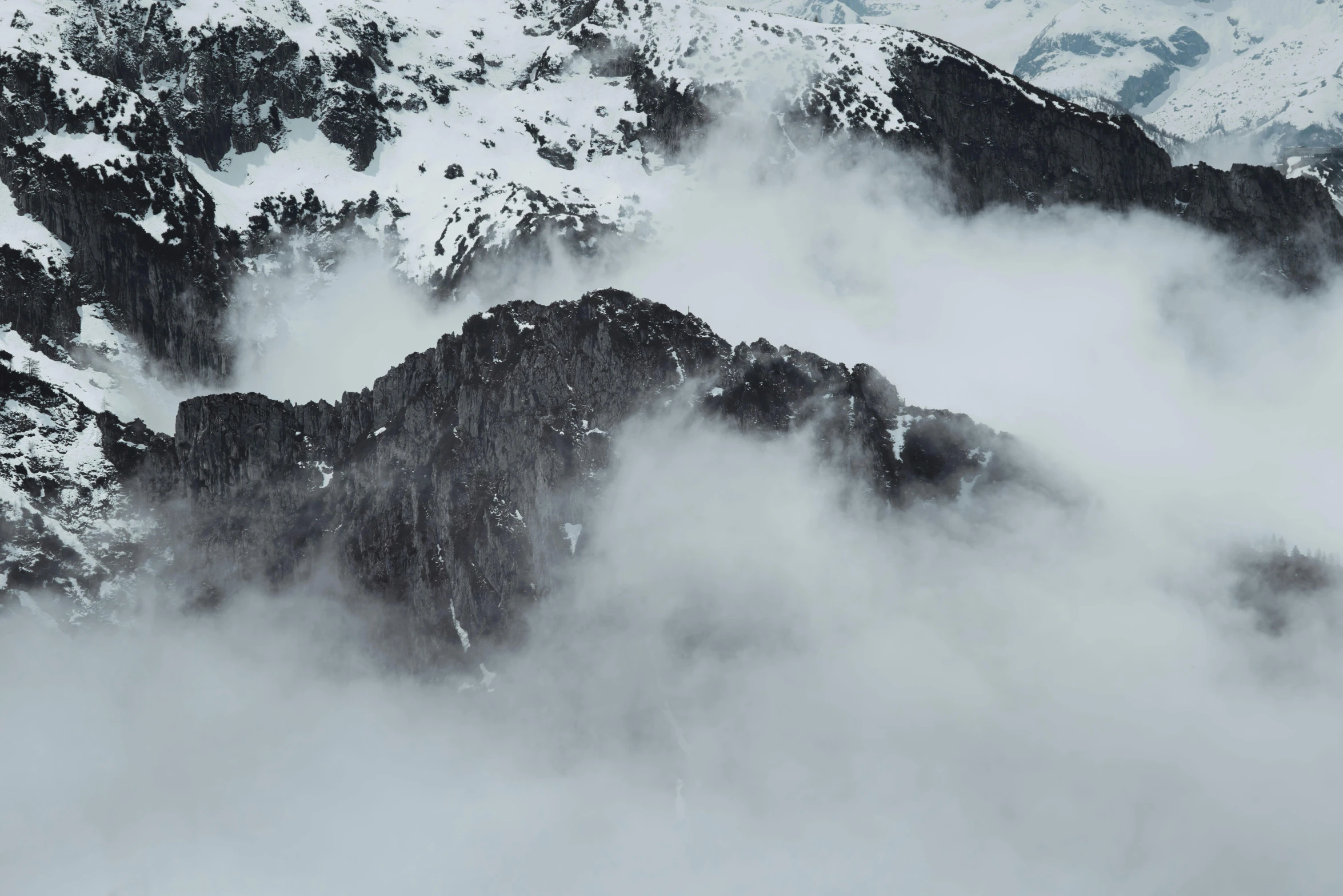 fog hanging over a snow covered mountain landscape