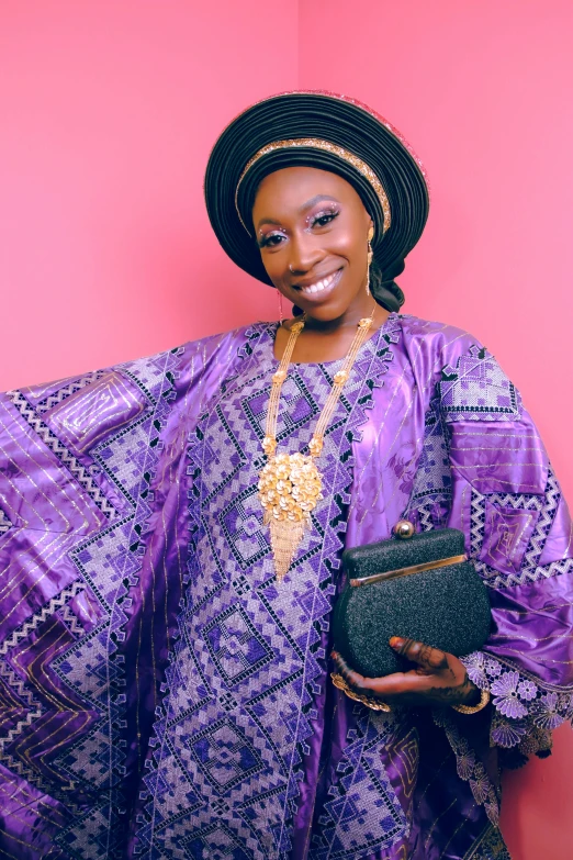 a woman wearing a purple african print dress and carrying a purse