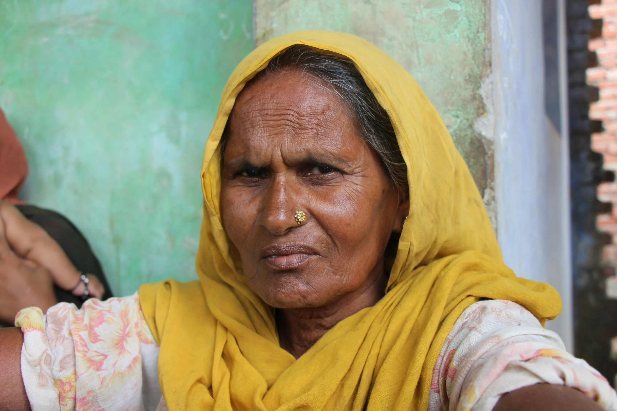 a person with a yellow head dress and one hand on the other shoulder