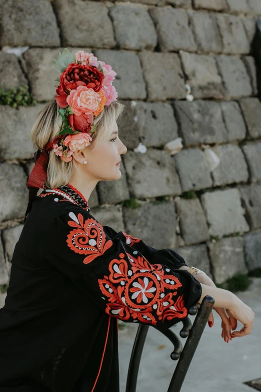 woman with red flowers in her hair sitting on chair outside