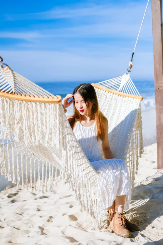 a girl laying in a hammock on the beach