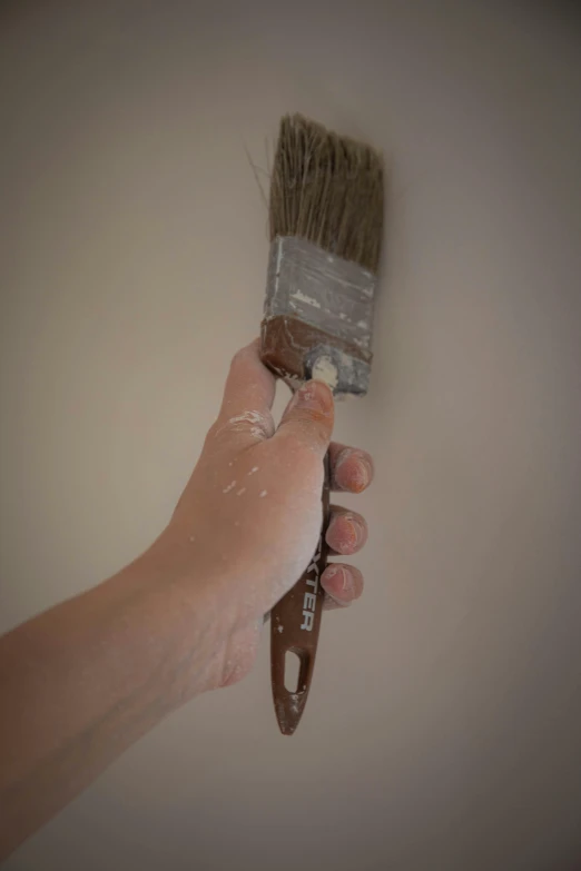 someone is holding a paintbrush that's leaking with brown liquid