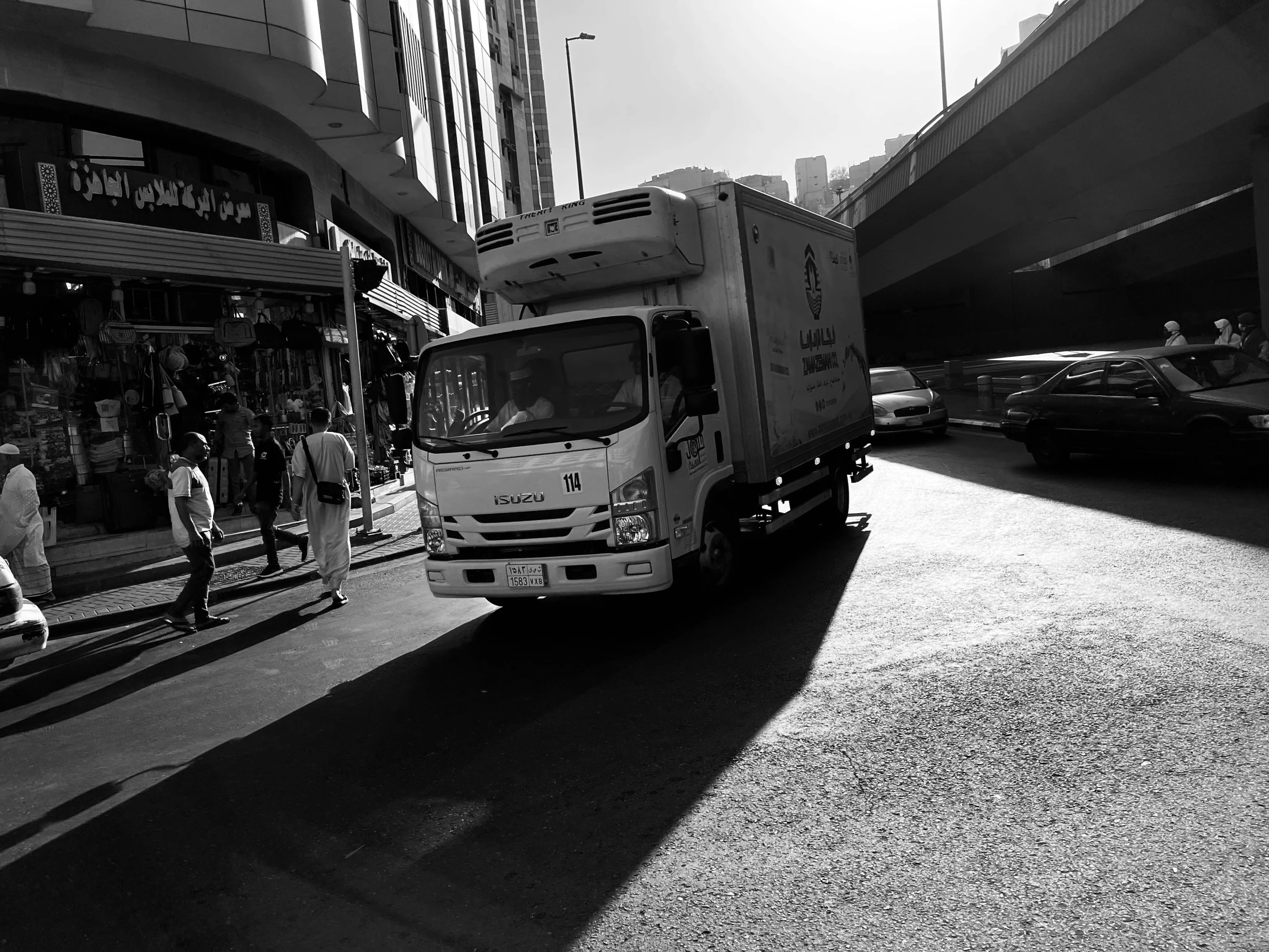 people walking by an empty city street next to a truck