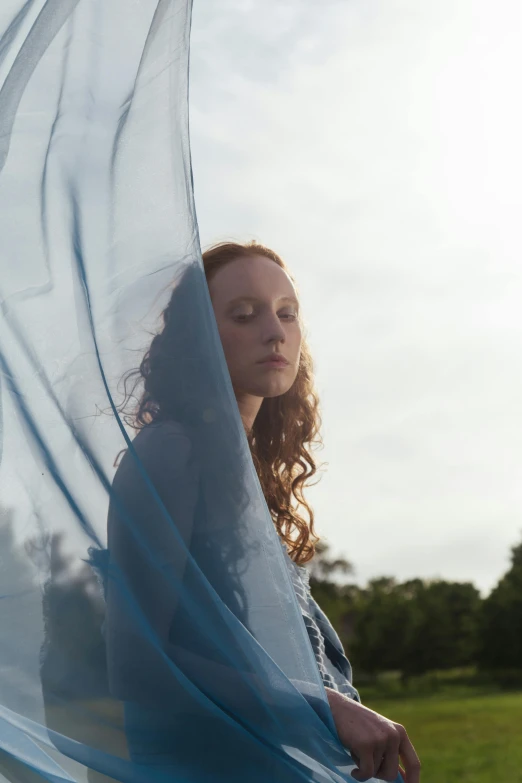 a woman is looking down through the blue sheer fabric