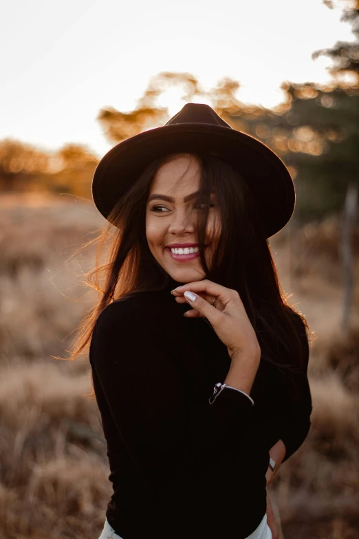 a woman in a hat smiles while she is outside