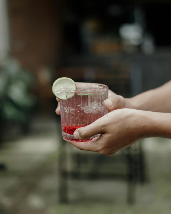 a hand holding a glass with some liquid in it