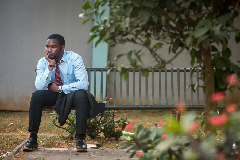 a man with a tie sits on a bench