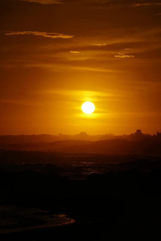 the setting sun in a city from the ocean