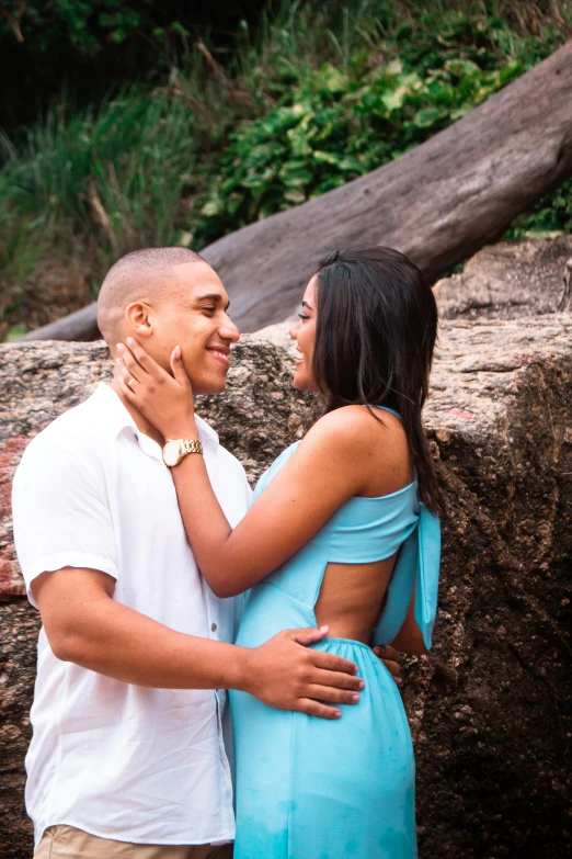 a couple is emcing in front of a rock