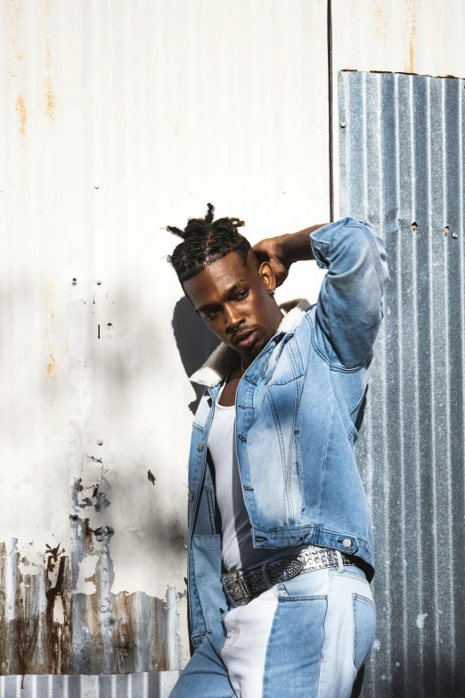 a man with mohawk hair leaning against a wall