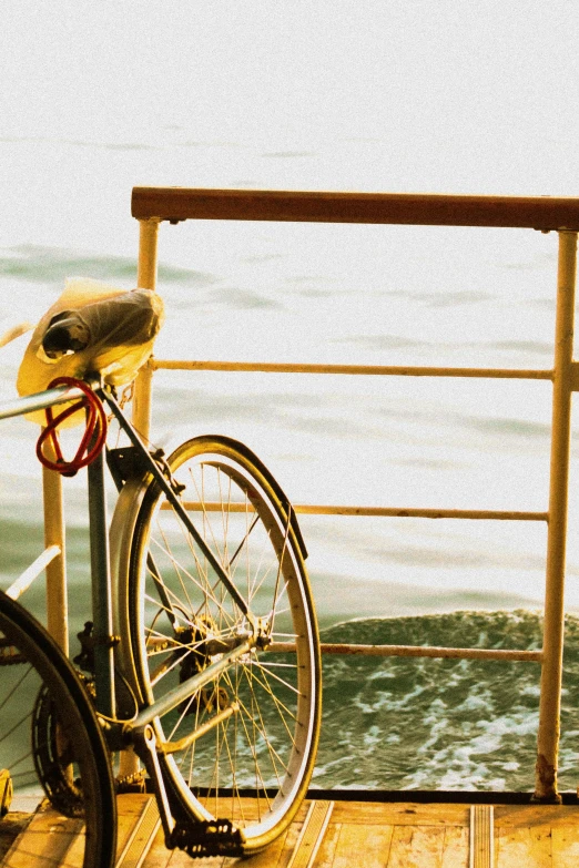 a bicycle leans on a rail near the ocean