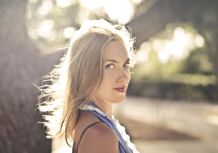 a young lady poses under the shade of a tree