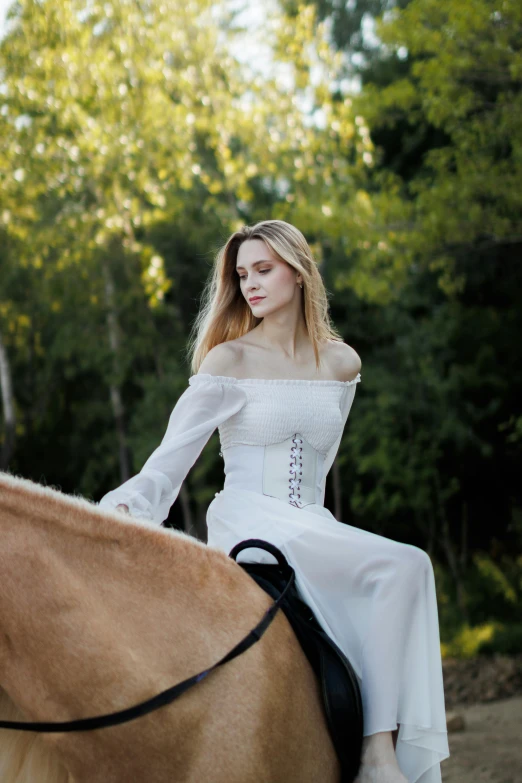 a woman with blond hair in a white dress is riding on a horse