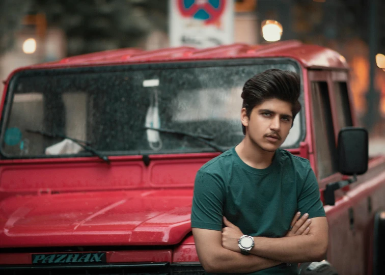 a man leaning his arms on his arms, and a red pickup truck in the background