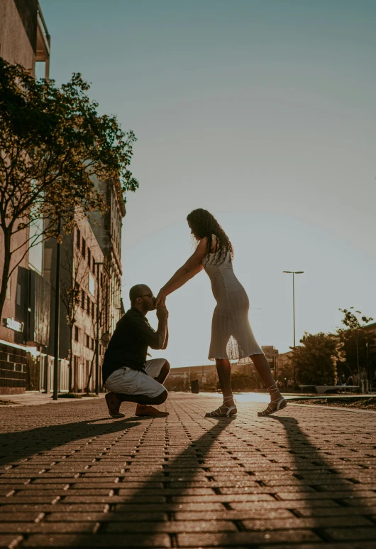 a man kneeling on the ground with another man in a white shirt