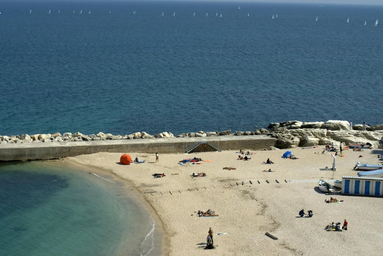 several people and small boats on the water next to a beach