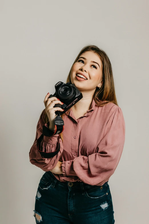 a woman holding a camera and posing for a po