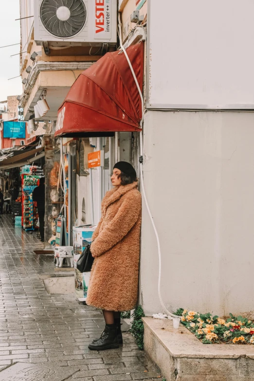 a woman is leaning against a building near a street