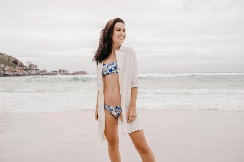 a woman standing on top of a beach next to the ocean