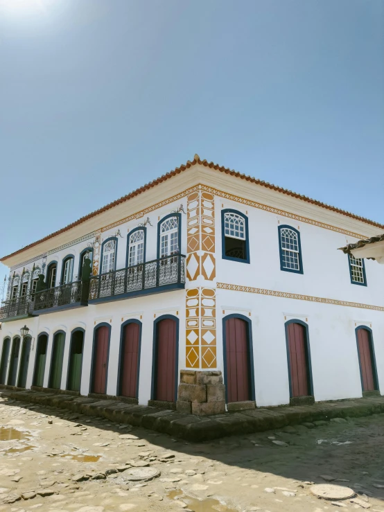 a white building with black and red doors and balcony