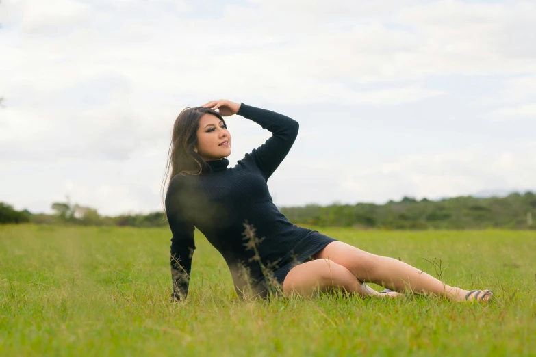 a woman is sitting on the grass and looking at soing