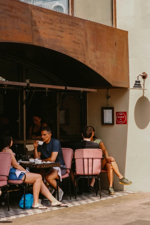 people sitting around a small cafe with pink chairs