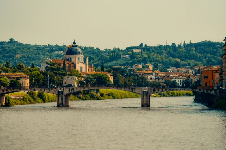 the river flows past some buildings on a hill side