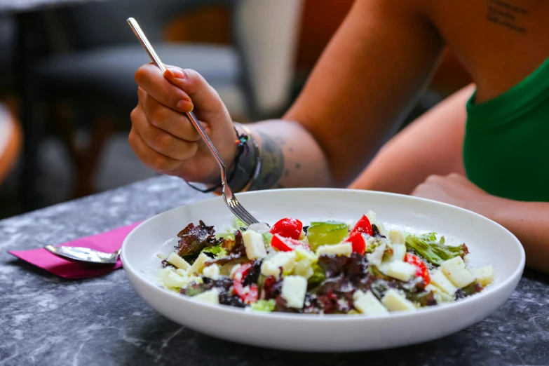 a person sitting in front of a bowl of salad