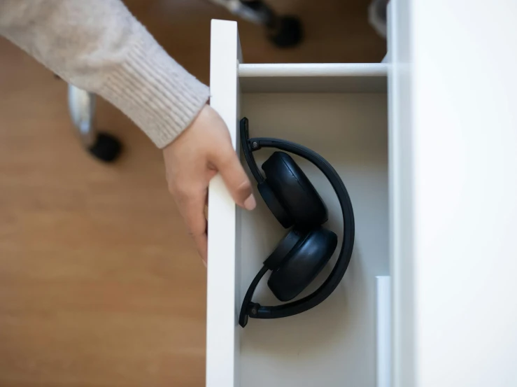 a hand is opening an open drawer with two headsets