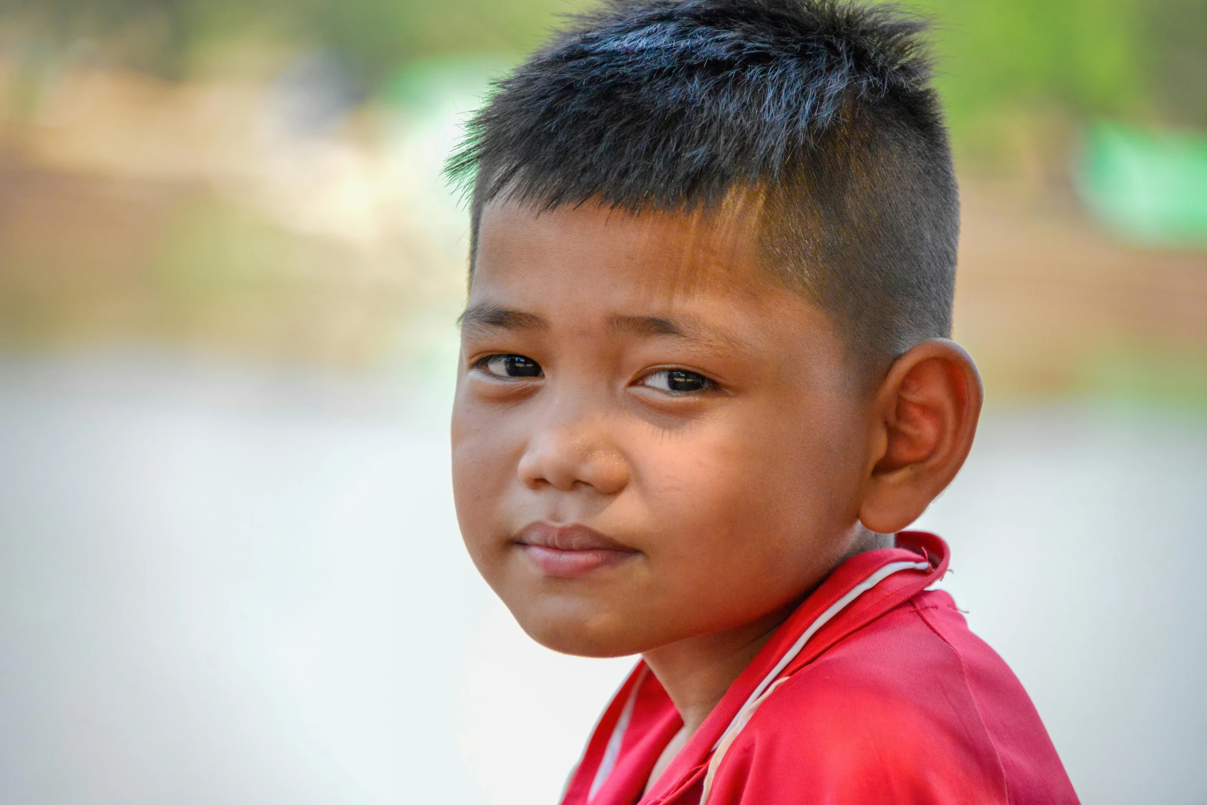 a child with a red shirt is smiling at the camera