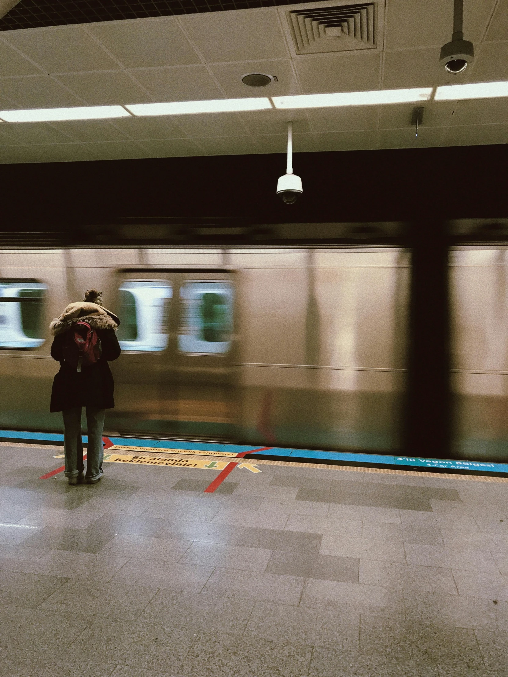 a person on a train platform with a backpack and a bag