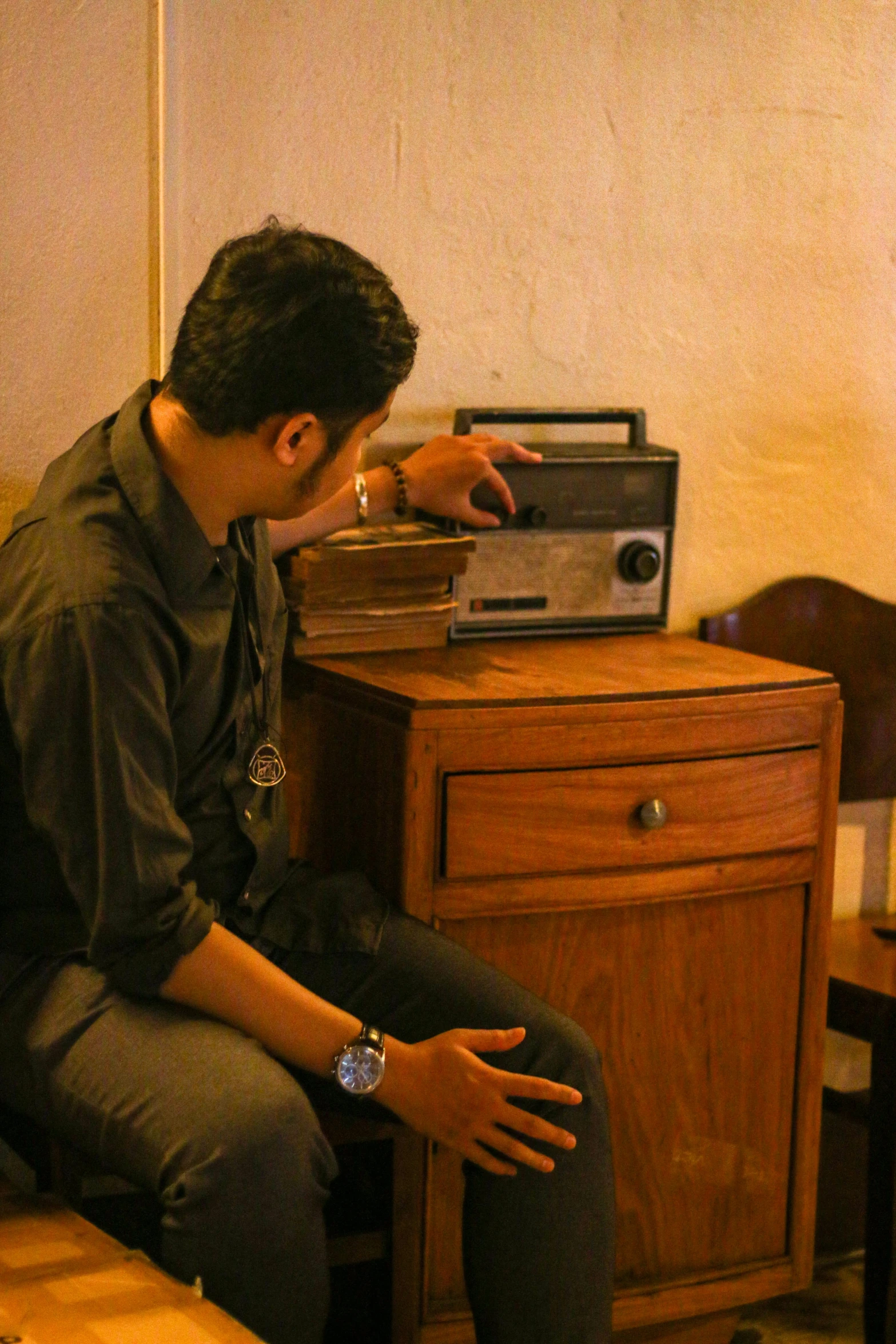 a person sitting on a wooden chair looking at a radio