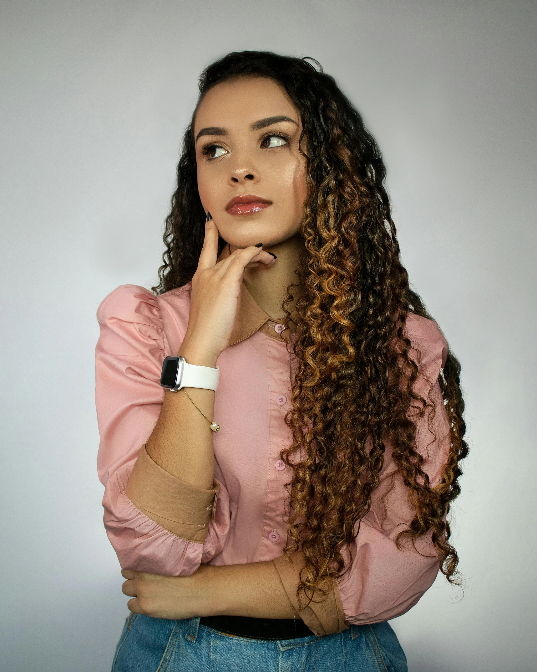 a young woman with brown curly hair in a pink shirt poses for the camera