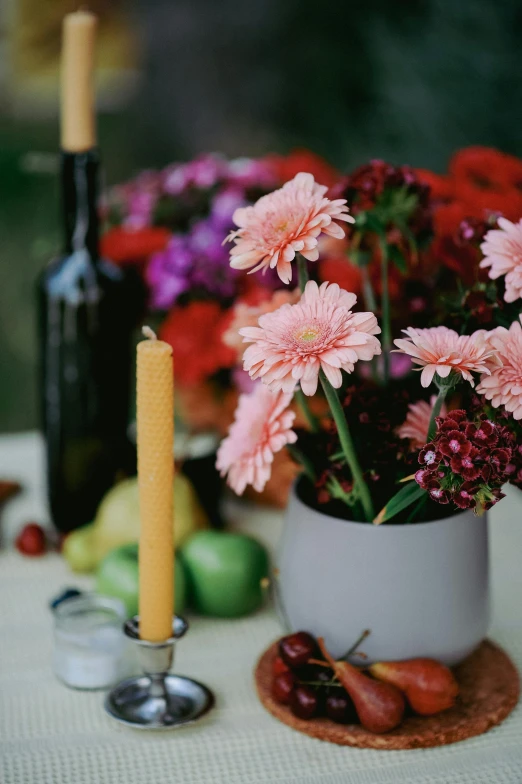 there is a wine bottle, a glass and flowers in a vase