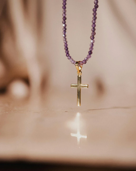 a purple beaded necklace with a cross attached